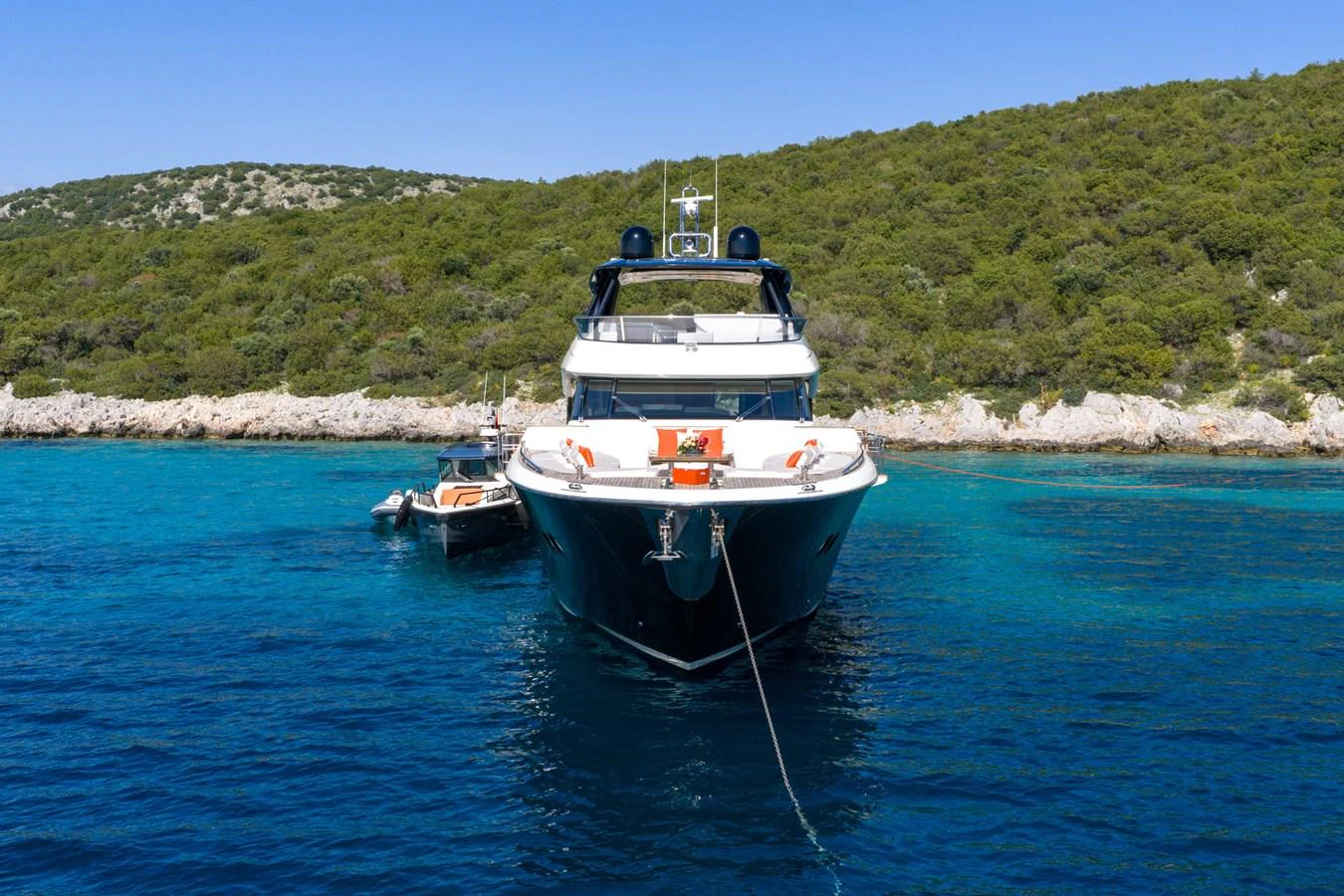 A luxurious yacht anchored in clear blue waters near a scenic coastline. aboard BELLA LUNA Yacht for Sale