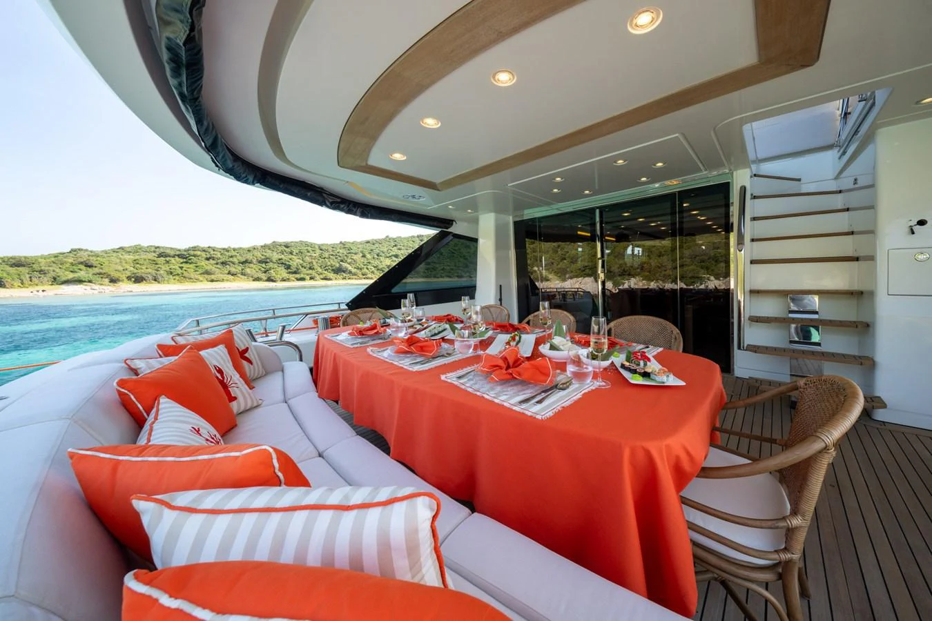 The aft deck features a stylish dining area with vibrant orange accents and comfortable seating. aboard BELLA LUNA Yacht for Sale