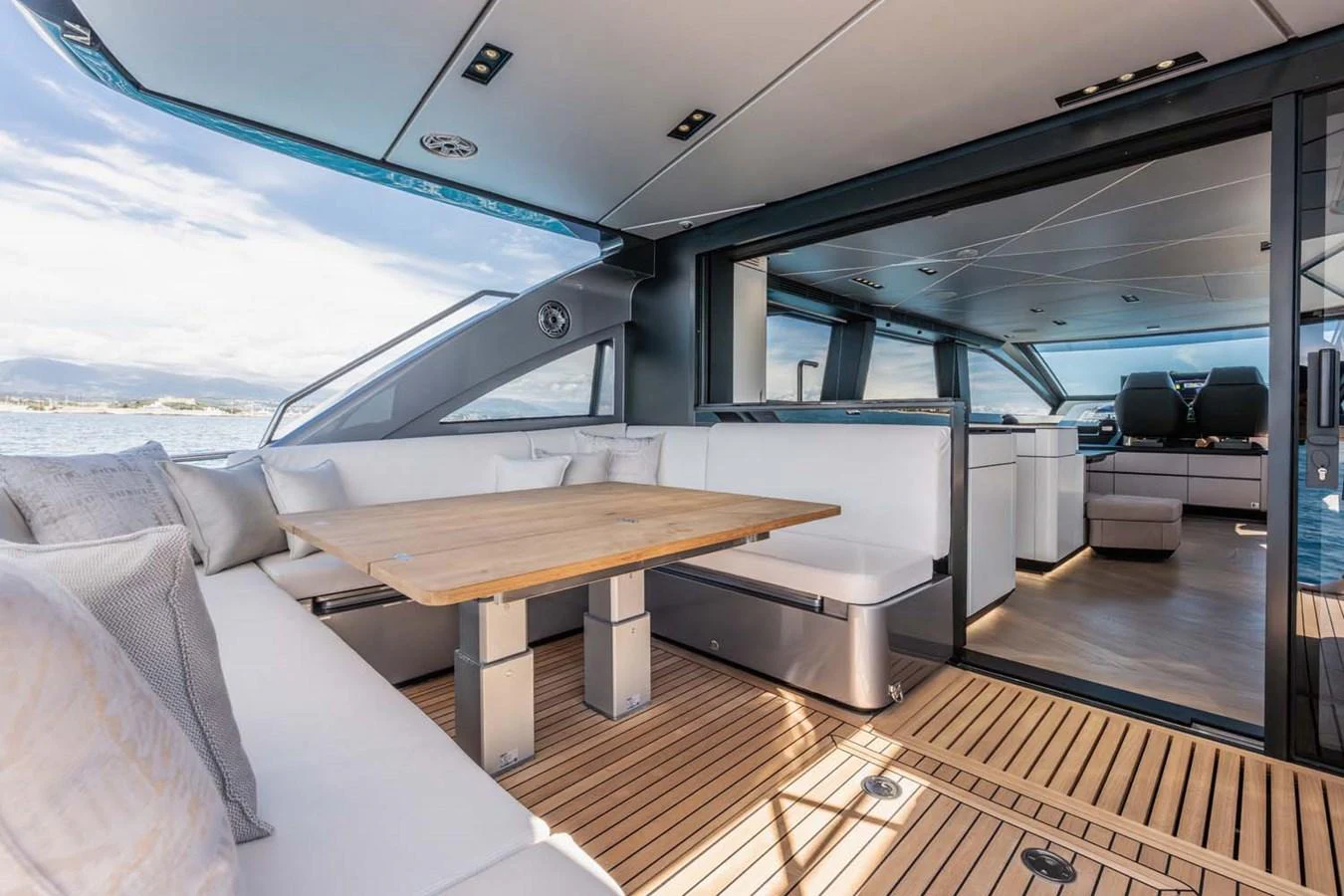 The aft deck features a spacious seating area with a wooden table, seamlessly blending indoor and outdoor spaces. aboard REEMA Yacht for Sale