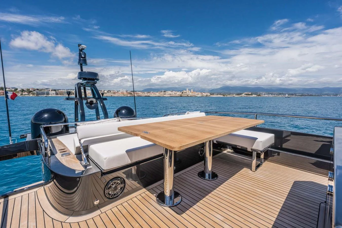 The aft deck features a spacious seating area with a wooden table, perfect for alfresco dining with stunning ocean views. aboard REEMA Yacht for Sale