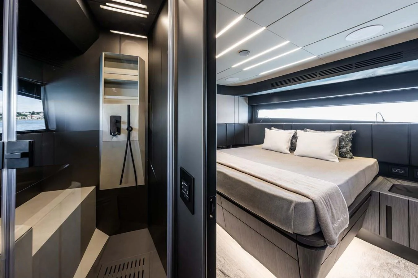 The image showcases a modern stateroom with a luxurious bed and an adjacent sleek bathroom area. aboard REEMA Yacht for Sale