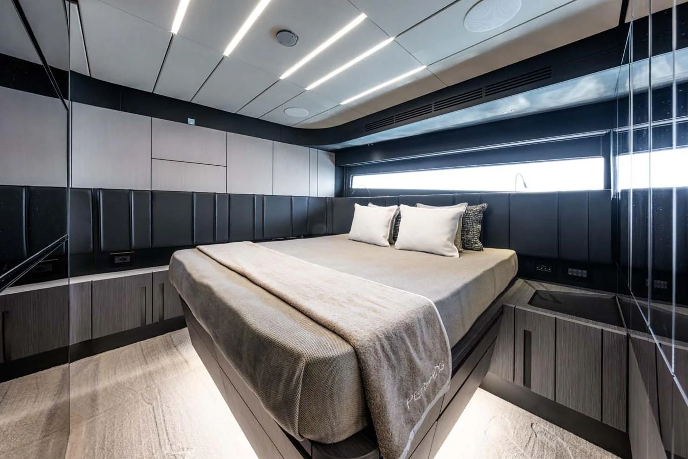The stateroom features a luxurious bed with modern lighting and sleek design elements. aboard REEMA Yacht for Sale