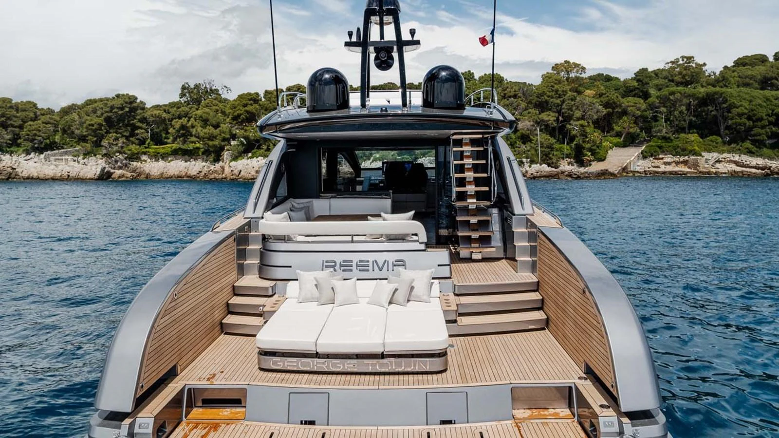 The yacht's aft deck features luxurious seating and sunbathing areas with a scenic backdrop. aboard REEMA Yacht for Sale