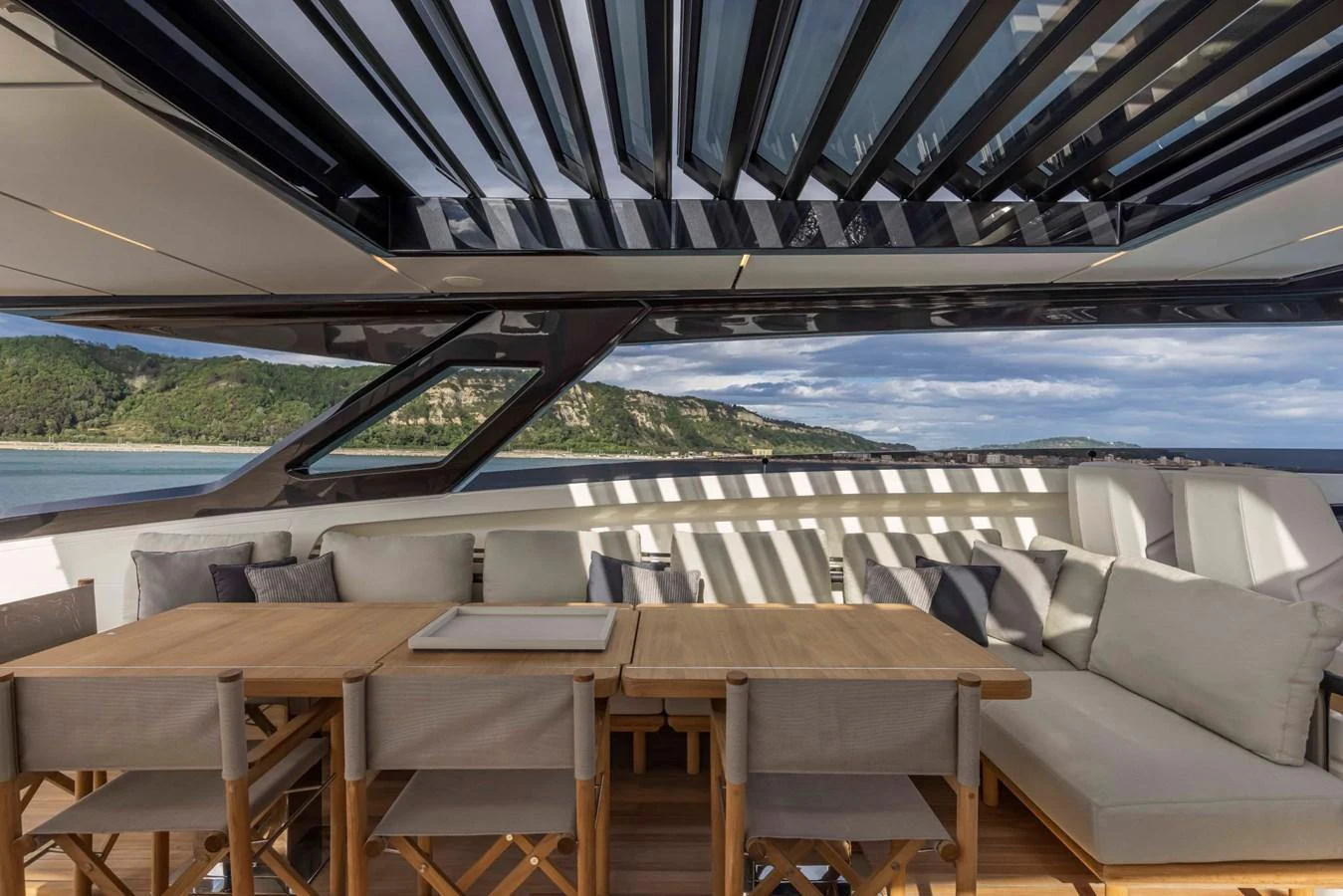 The aft deck features a spacious seating area with a wooden dining table and comfortable chairs, perfect for outdoor relaxation and dining. aboard DANIMA Yacht for Sale