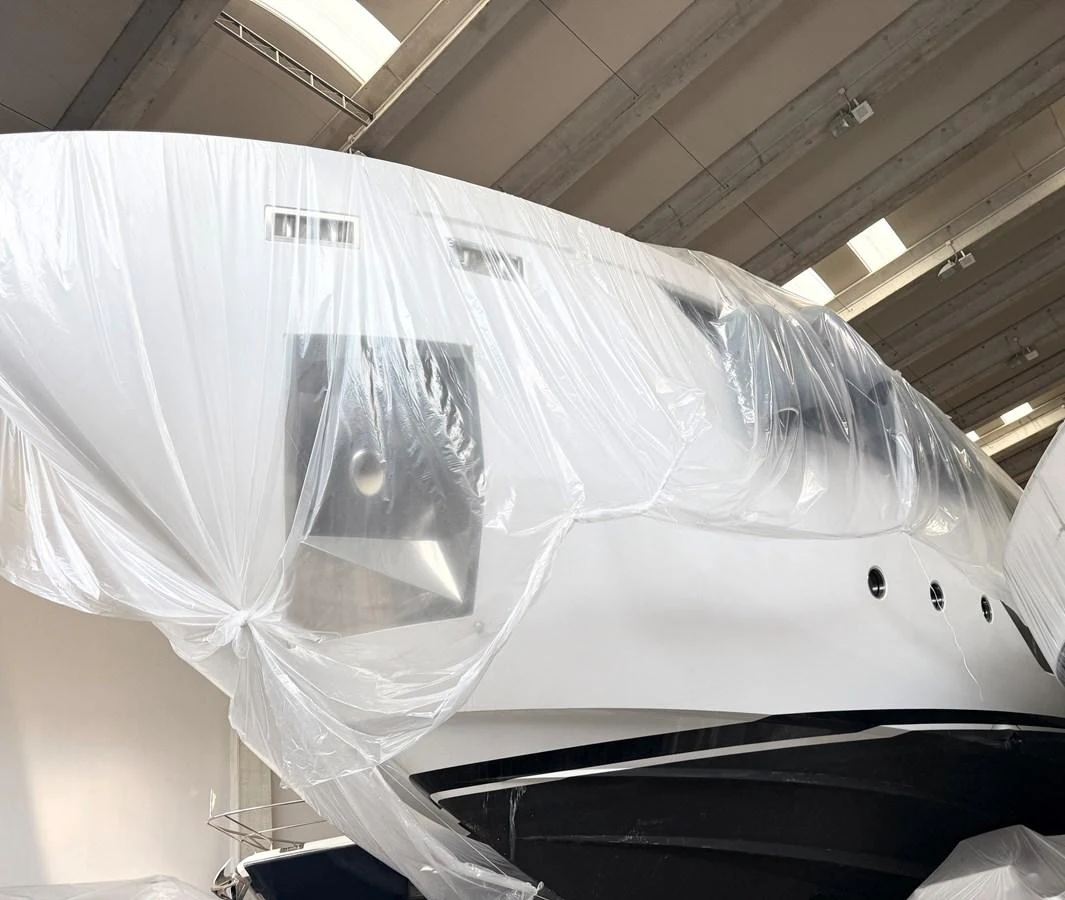The yacht is partially covered in protective plastic sheeting, likely in a storage or maintenance facility. aboard DANIMA Yacht for Sale