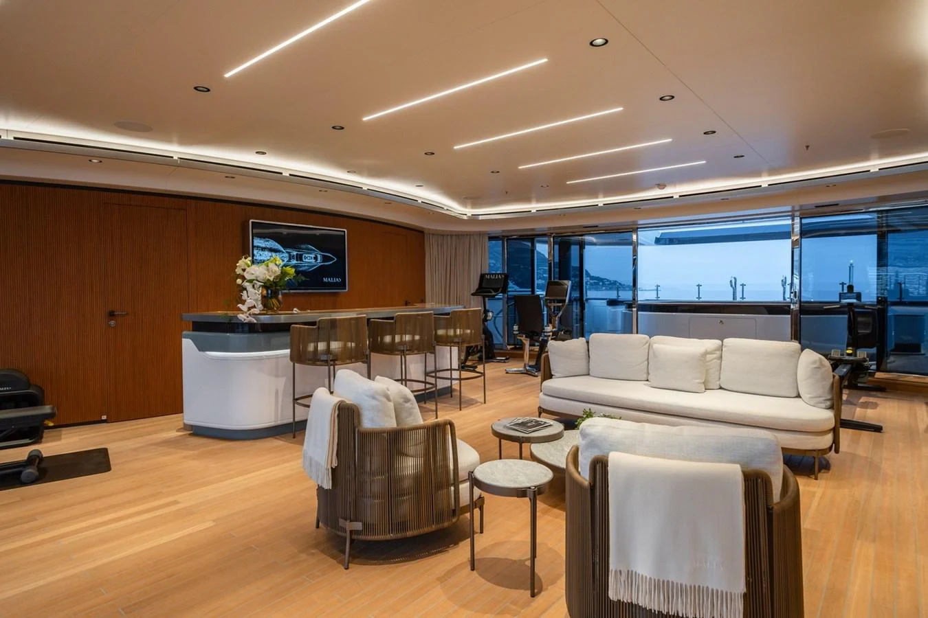 The spacious interior features a modern lounge area with a bar and fitness equipment, offering a blend of relaxation and activity. aboard MALIA Yacht for Sale