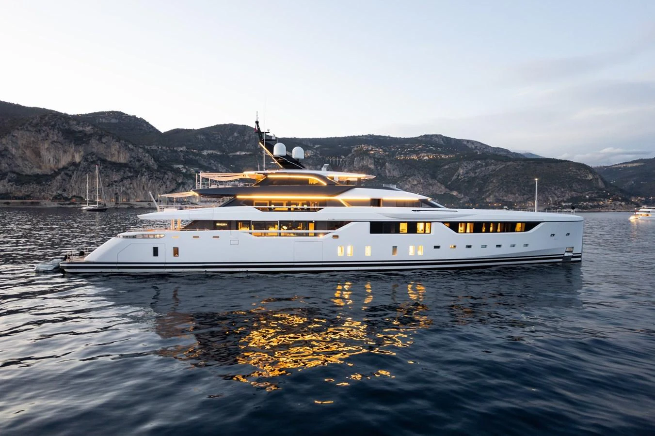 A sleek and modern yacht glides gracefully on calm waters against a scenic coastal backdrop. aboard MALIA Yacht for Sale
