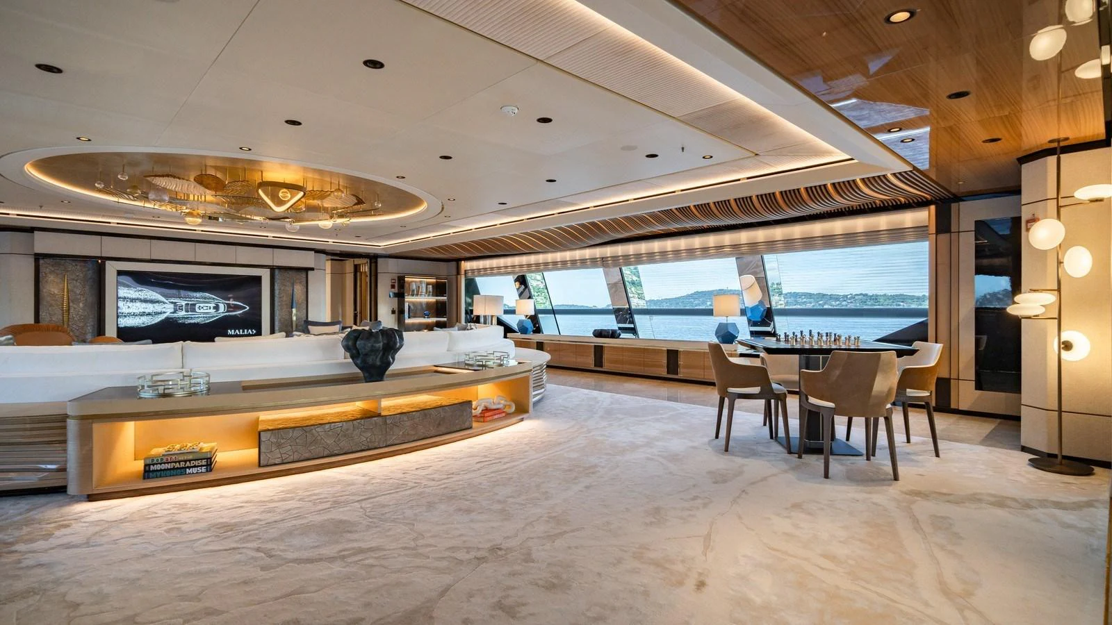 The spacious salon features luxurious seating, a dining area, and large windows offering stunning views. aboard MALIA Yacht for Sale