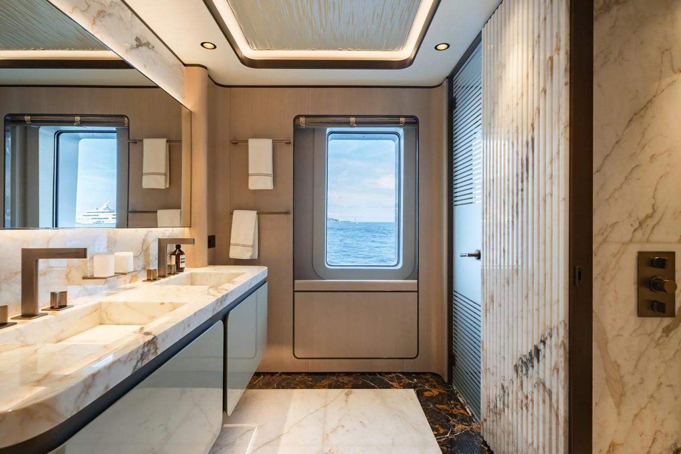 The bathroom features luxurious marble finishes and a window with a stunning sea view. aboard MALIA Yacht for Sale