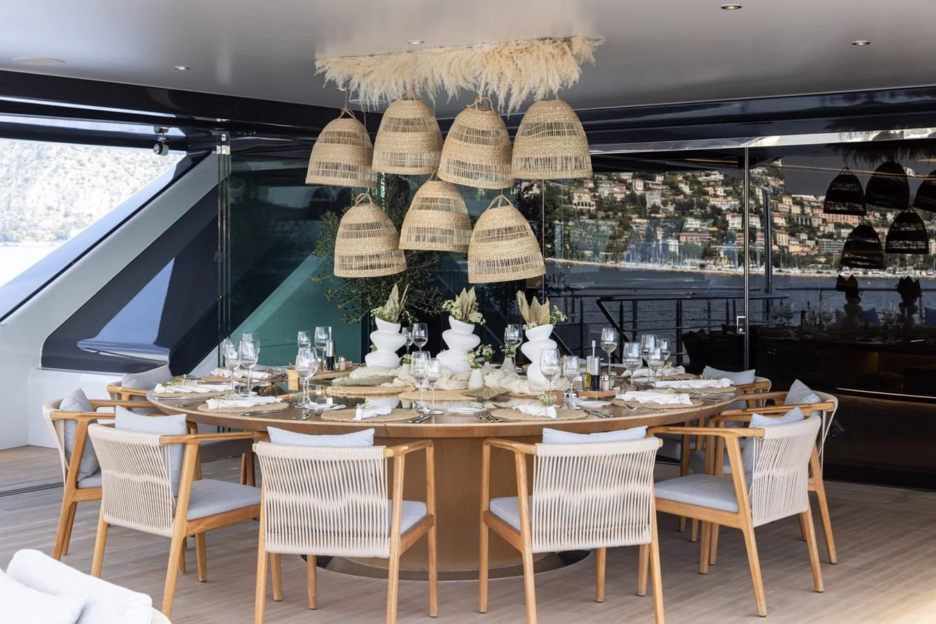 An elegant dining area on the yacht features a large round table with stylish wicker chairs and hanging pendant lights. aboard MALIA Yacht for Sale