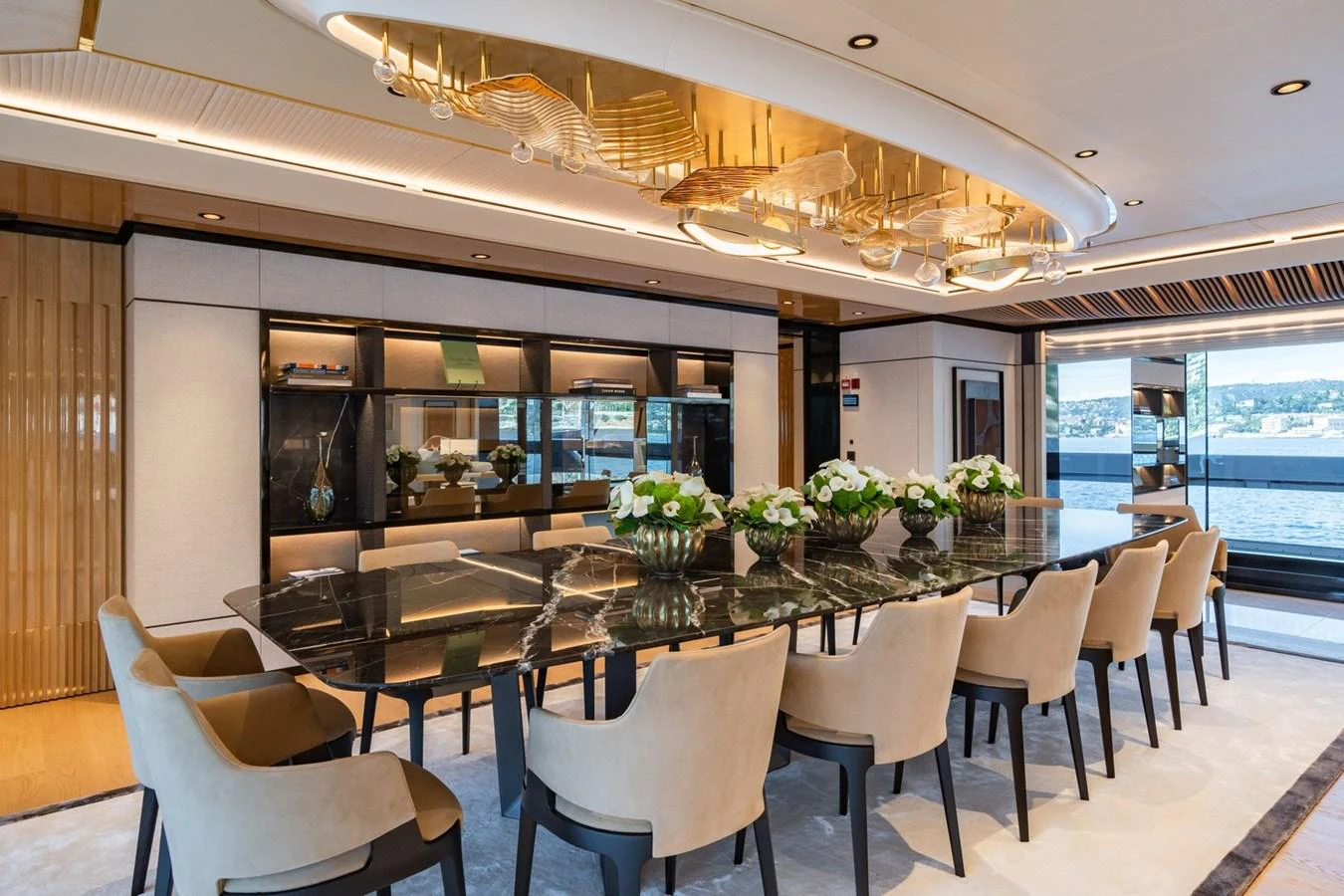 The luxurious dining area features an elegant table with plush seating and a stunning ceiling fixture. aboard MALIA Yacht for Sale