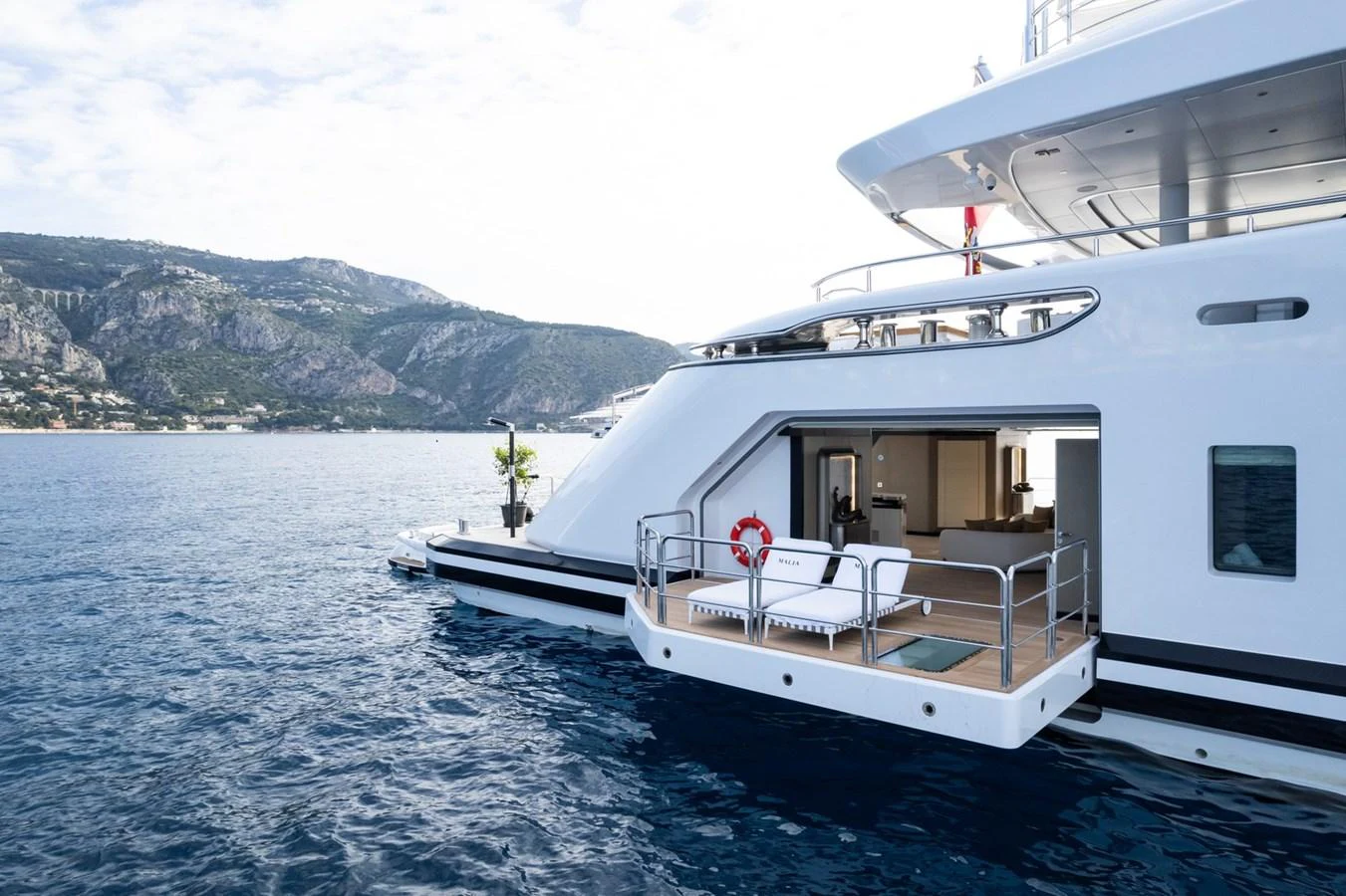 The yacht features a spacious aft deck with a lounging area and direct access to the water. aboard MALIA Yacht for Sale