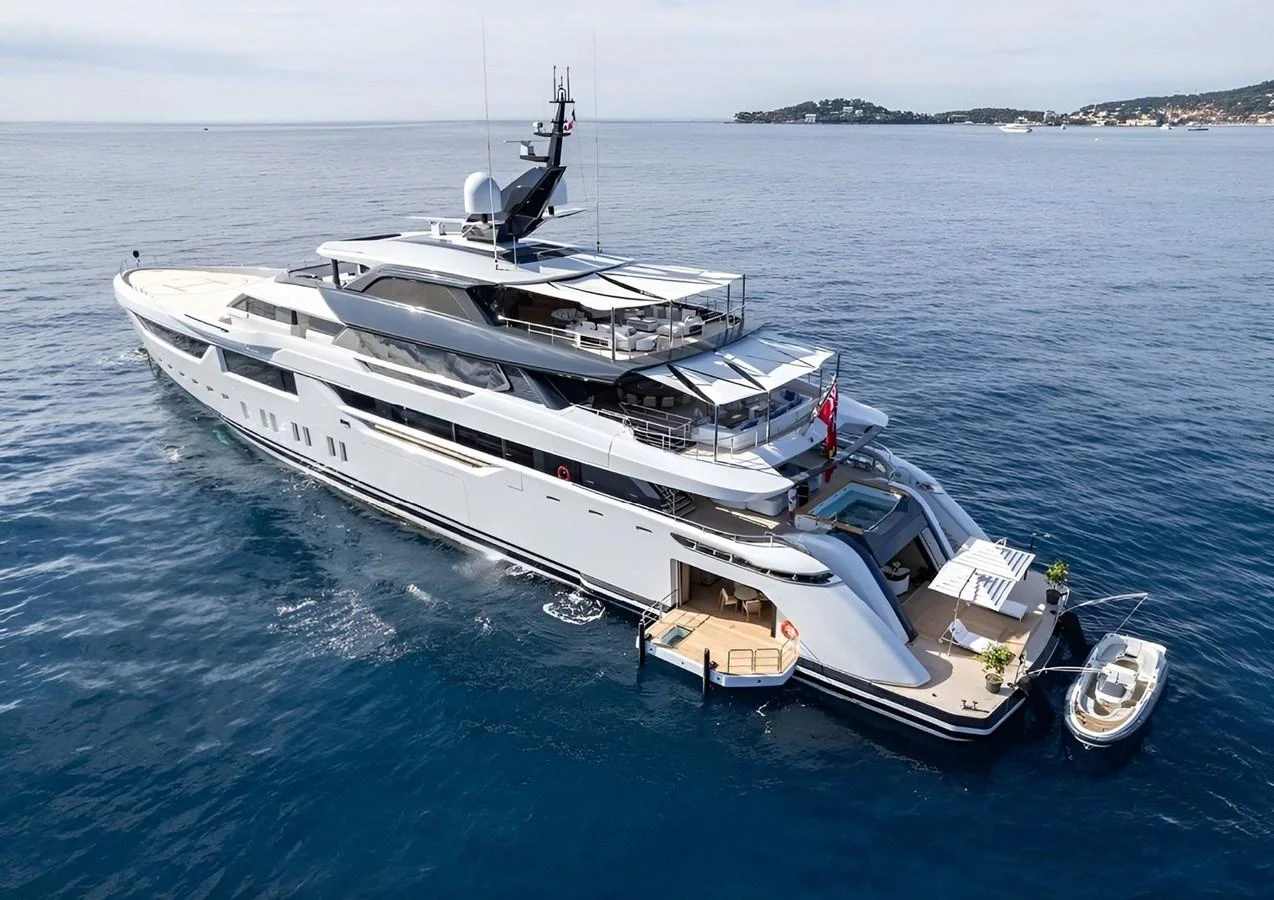 A sleek and modern yacht cruising on calm blue waters with a tender docked at the stern. aboard MALIA Yacht for Sale