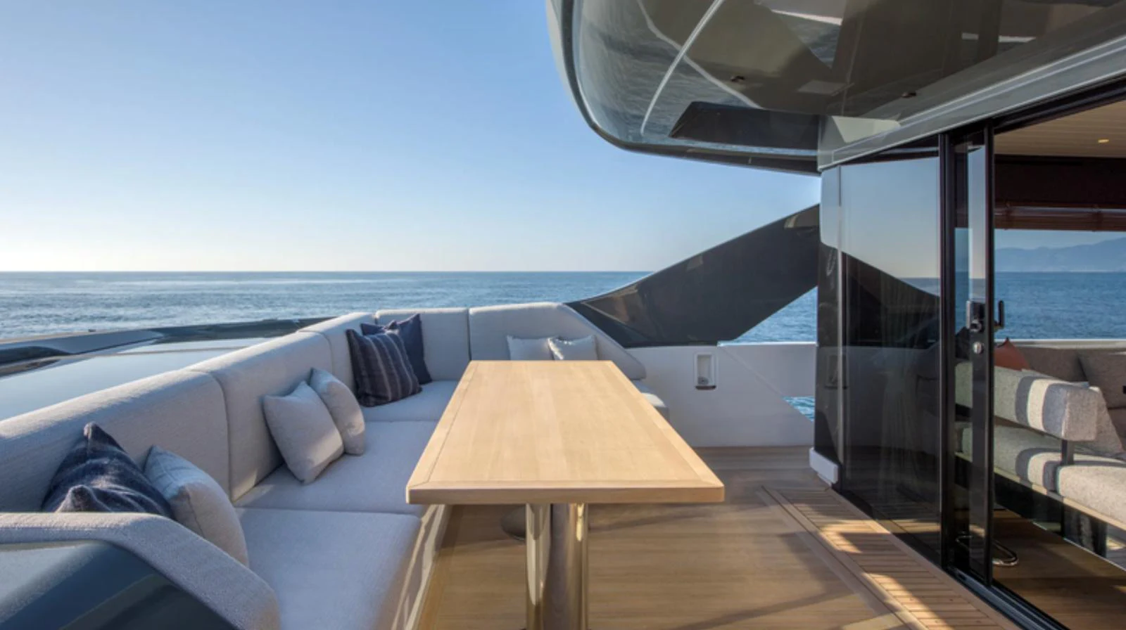 The aft deck features a spacious seating area with a wooden table, perfect for enjoying the ocean view. aboard BARIC Yacht for Sale