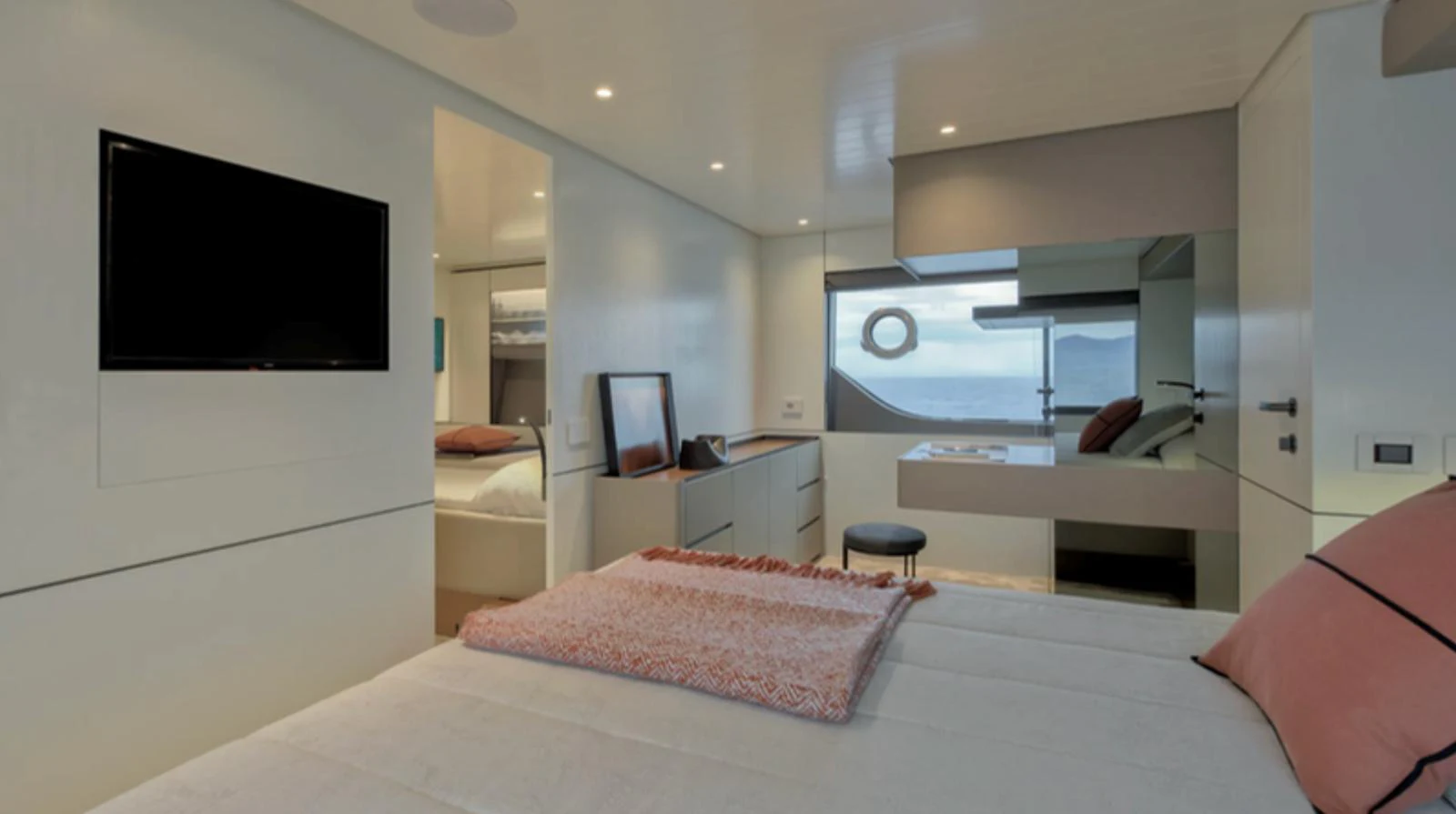 The stateroom features a modern design with a large bed, a flat-screen TV, and a view of the sea through a window. aboard BARIC Yacht for Sale