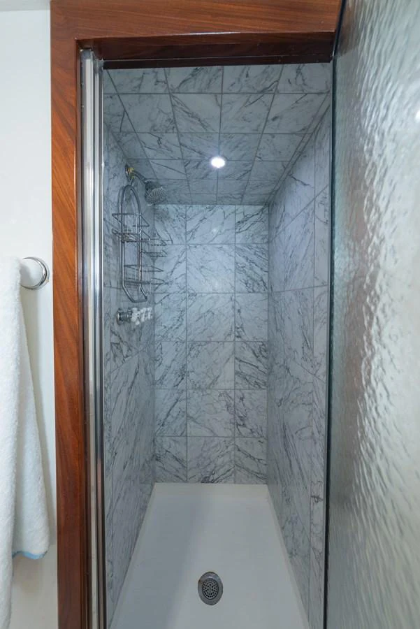 A sleek, marble-tiled shower area with modern fixtures. aboard INNISFAIL Yacht for Sale