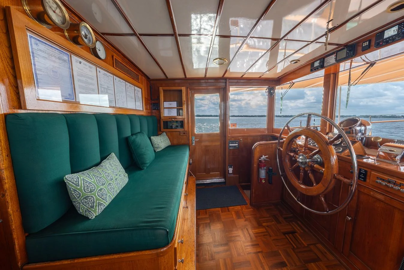 The helm features classic wooden finishes and a comfortable seating area with a view of the sea. aboard INNISFAIL Yacht for Sale