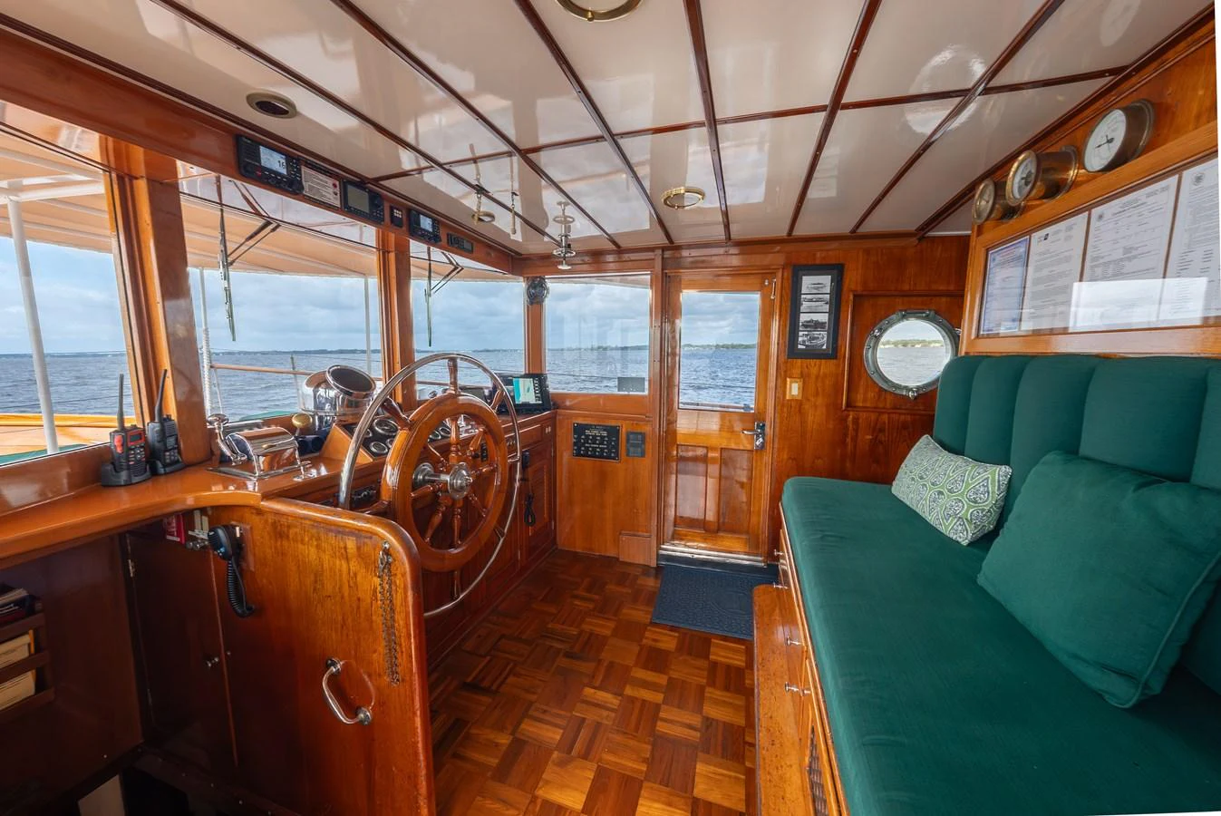The helm features classic wooden finishes and a comfortable seating area with ocean views. aboard INNISFAIL Yacht for Sale