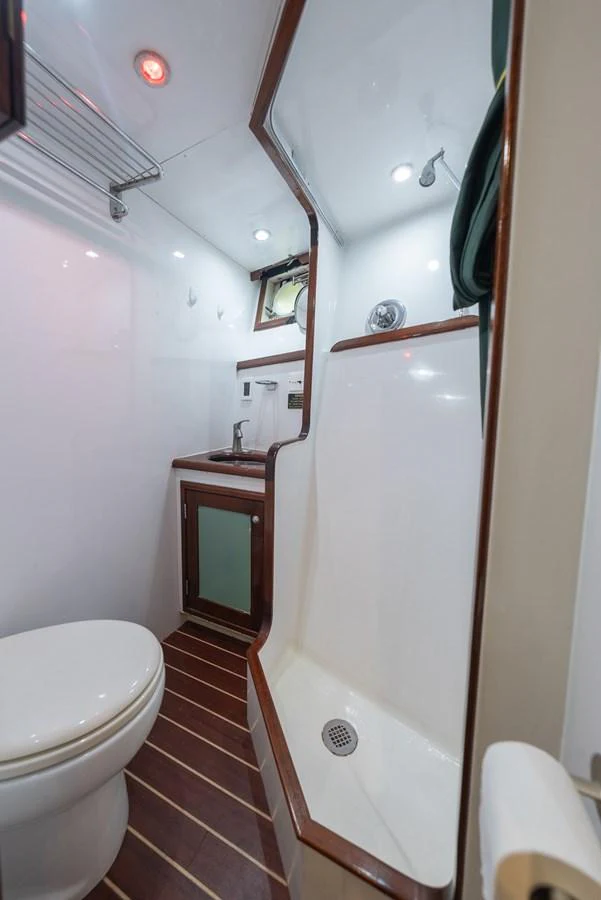 A compact and well-designed yacht bathroom featuring a shower, sink, and toilet with modern fixtures. aboard INNISFAIL Yacht for Sale