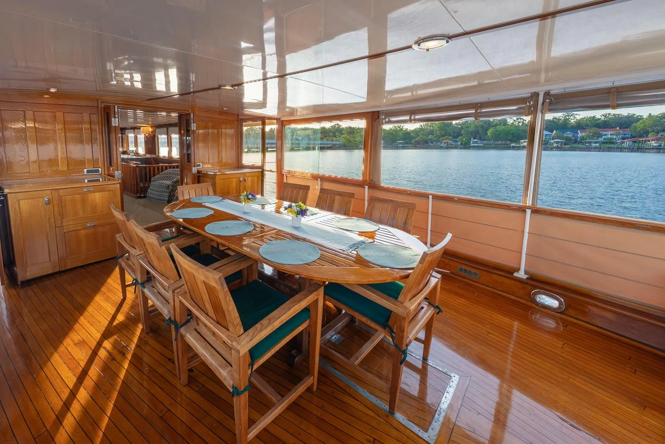 The yacht features a spacious and elegant dining area with a large table and wooden chairs, offering stunning views of the water. aboard INNISFAIL Yacht for Sale