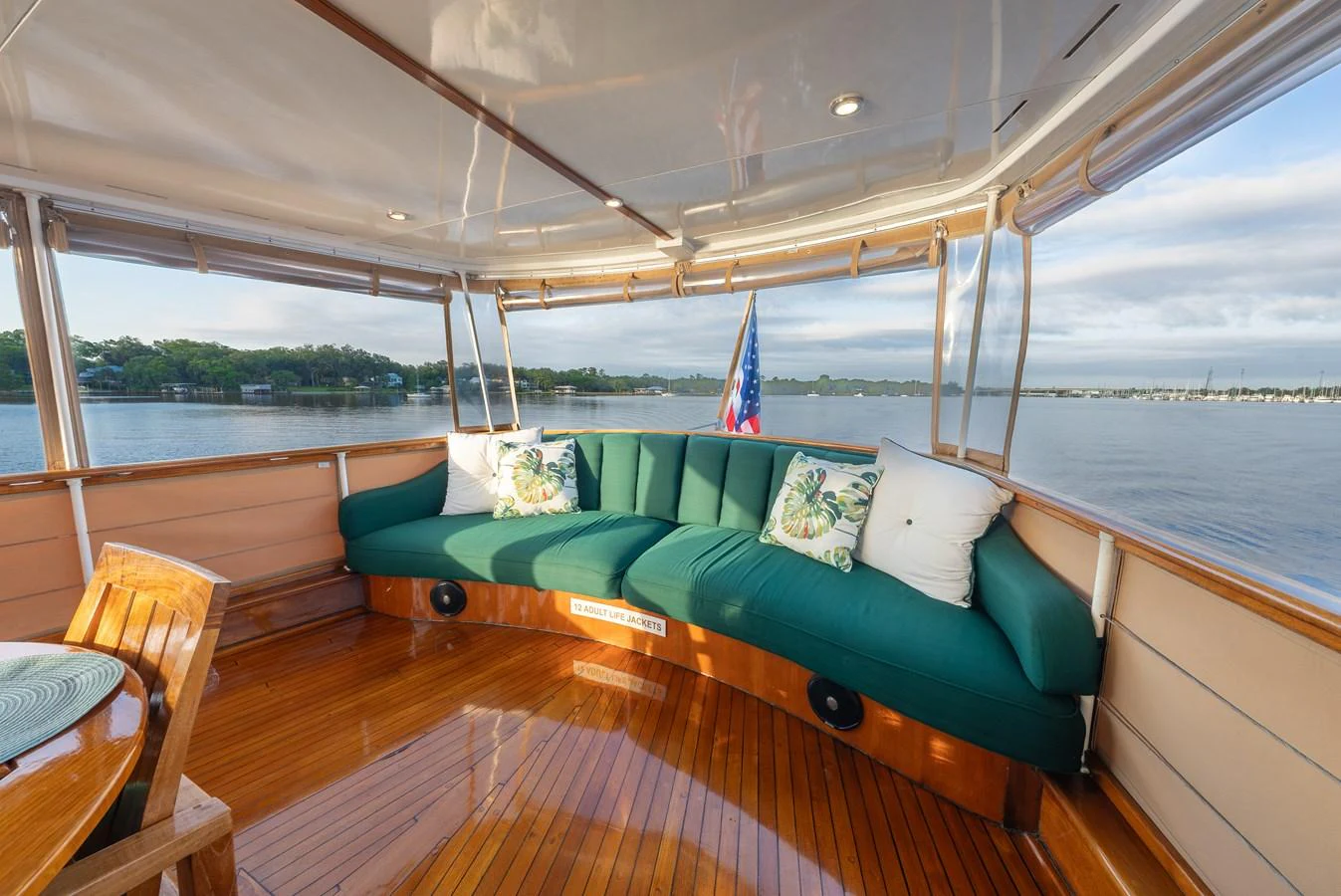 The aft deck features a cozy seating area with plush green cushions and a beautiful view of the water. aboard INNISFAIL Yacht for Sale