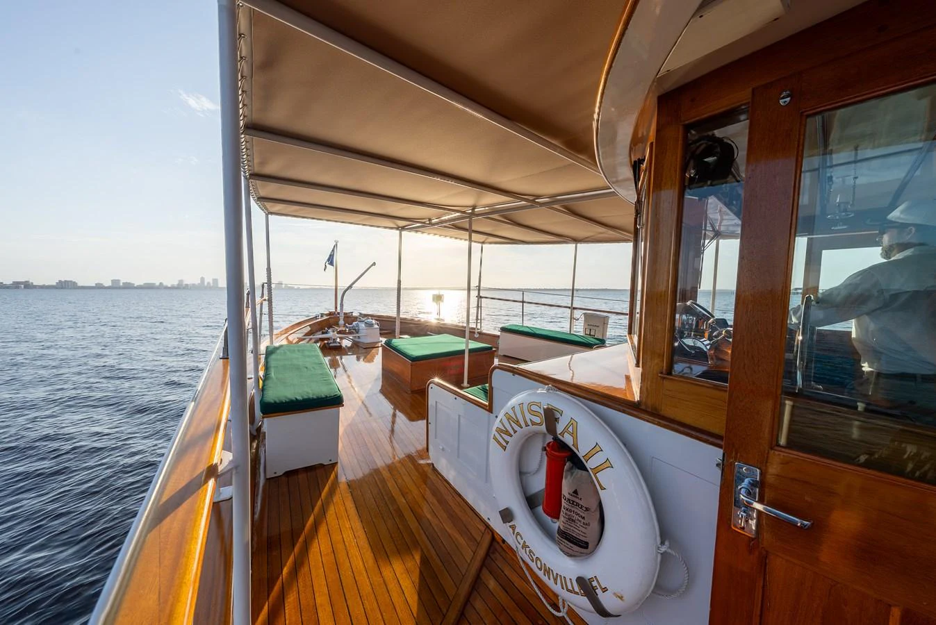 The aft deck of the yacht features comfortable seating and a polished wooden floor, perfect for enjoying the open sea. aboard INNISFAIL Yacht for Sale