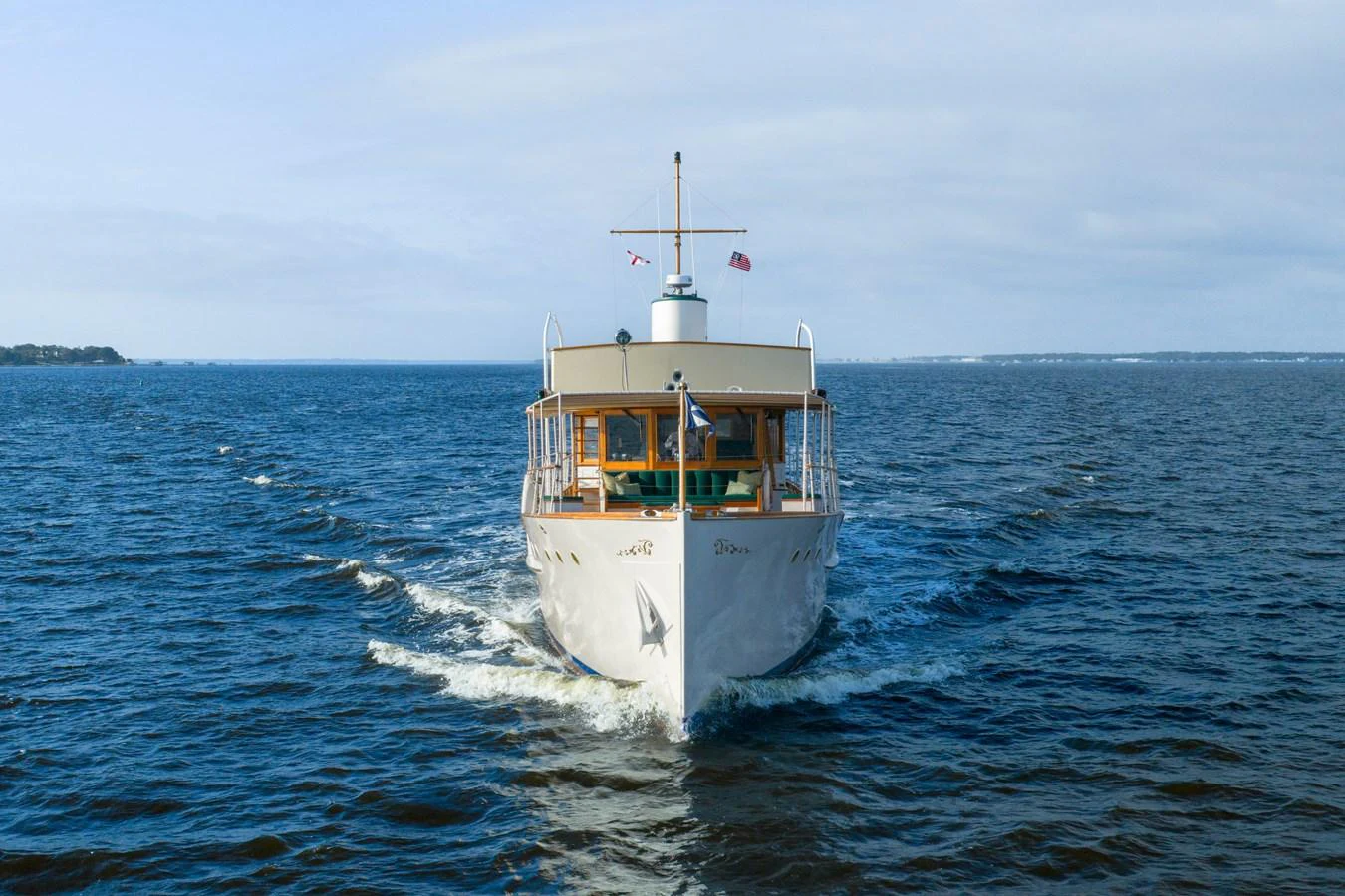 A classic yacht cruises gracefully on calm waters under a clear sky. aboard INNISFAIL Yacht for Sale