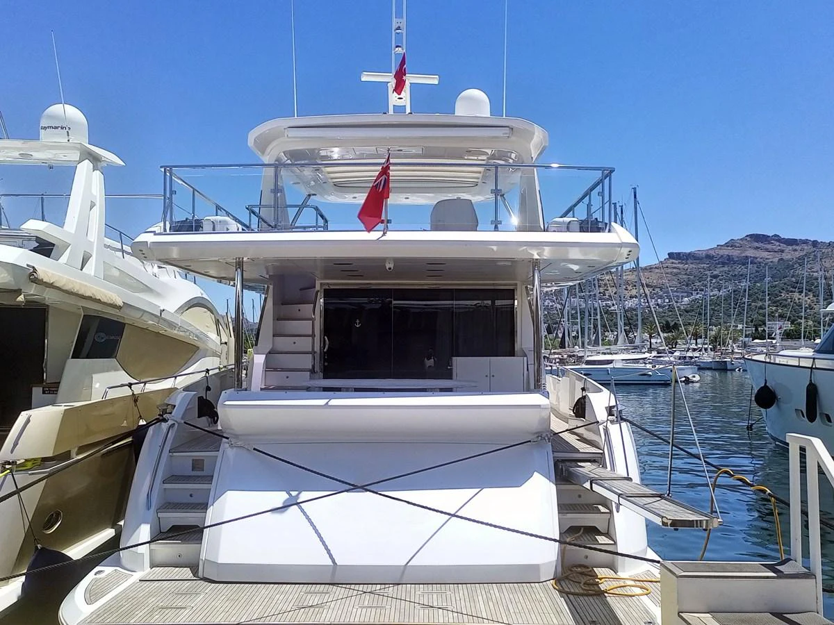 The yacht is docked at a marina, showcasing its spacious aft deck and sleek design. aboard LIL Yacht for Sale