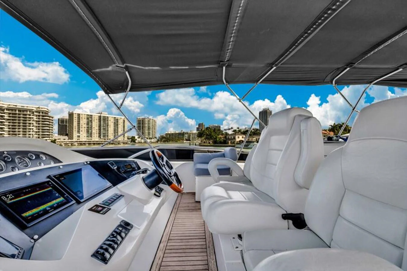 The helm station features plush seating and advanced navigation equipment under a protective canopy. aboard SO WHAT WHO CARES Yacht for Sale