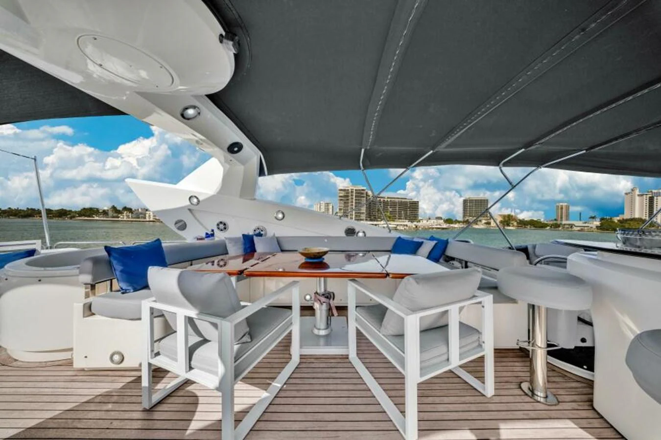 The aft deck features a stylish outdoor dining area with comfortable seating and a retractable canopy. aboard SO WHAT WHO CARES Yacht for Sale