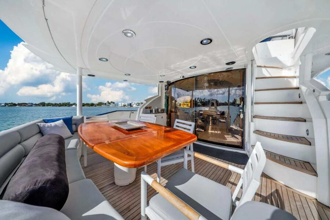 The aft deck features a comfortable seating area with a wooden dining table, perfect for outdoor meals and relaxation. aboard SO WHAT WHO CARES Yacht for Sale
