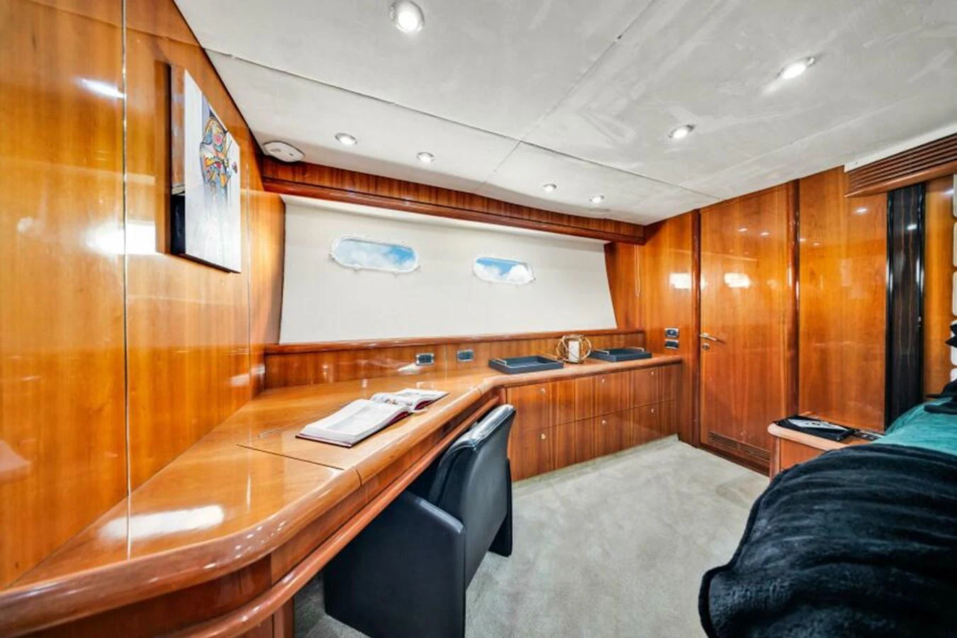 The yacht's interior features a well-appointed workspace with wooden cabinetry and comfortable seating. aboard SO WHAT WHO CARES Yacht for Sale