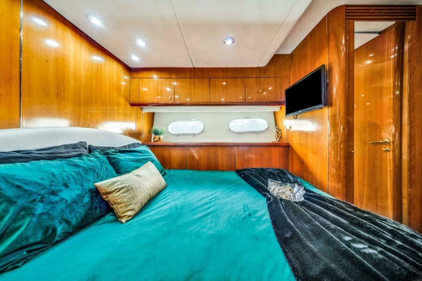 The stateroom features a luxurious bed with elegant bedding and warm wooden paneling. aboard SO WHAT WHO CARES Yacht for Sale