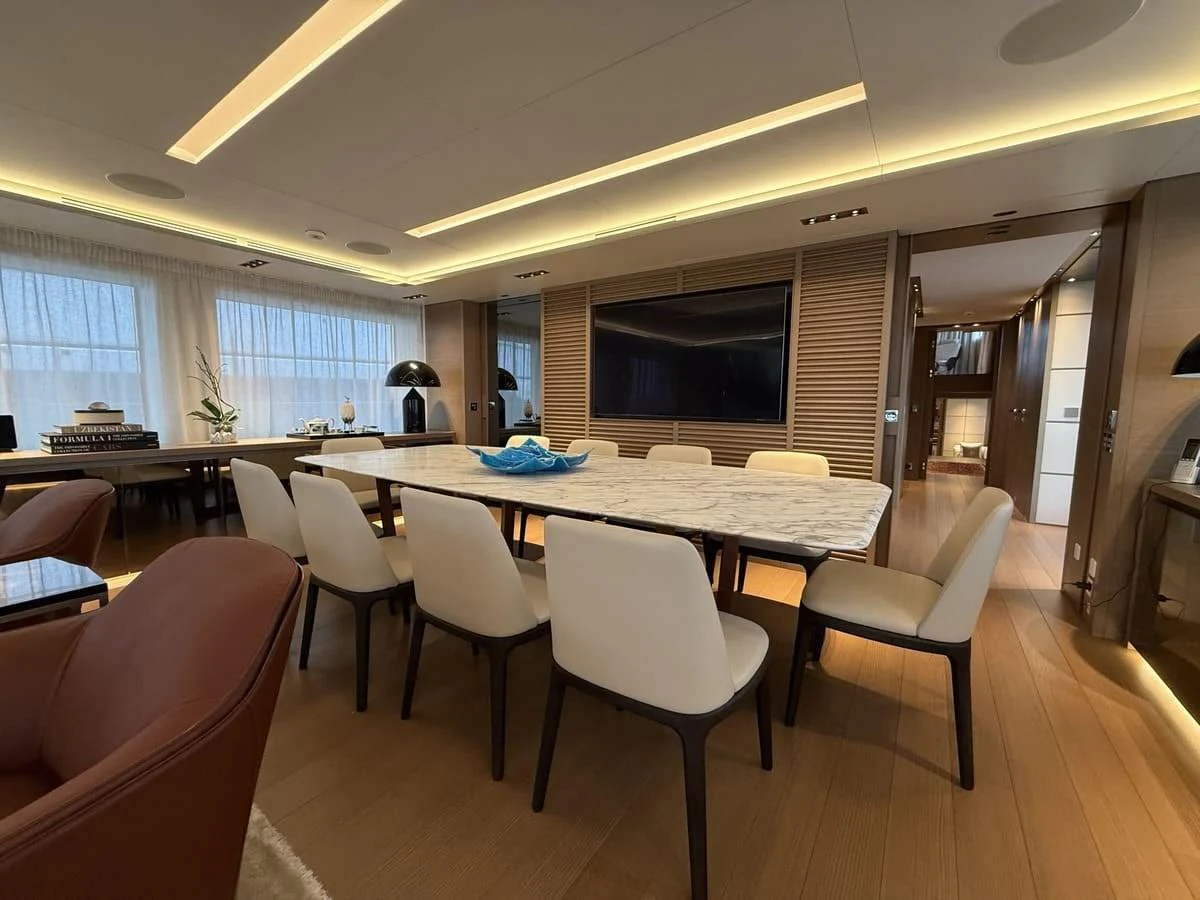The yacht's dining area features a large table with elegant seating, surrounded by warm lighting and modern decor. aboard PHOENICIAN Yacht for Sale