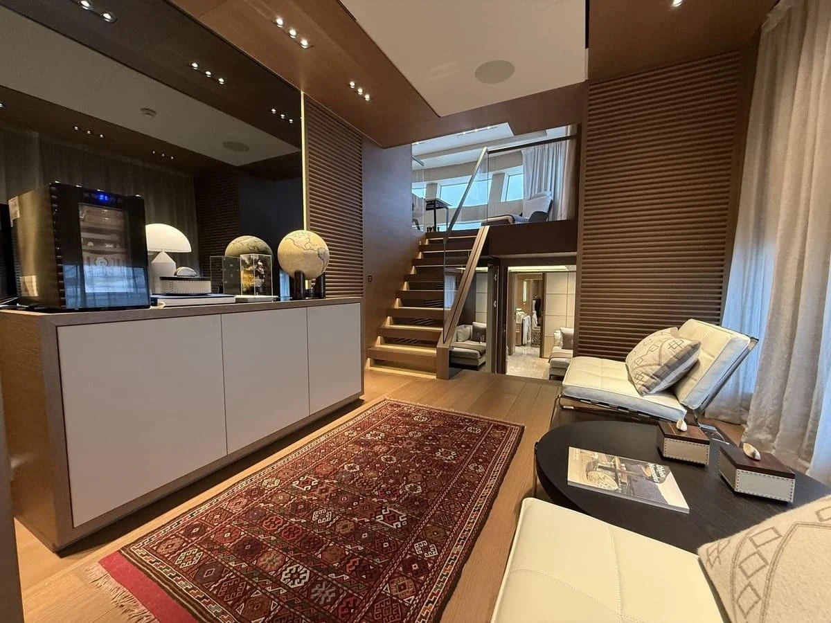 The yacht's interior features a cozy lounge area with modern furnishings and a staircase leading to another level. aboard PHOENICIAN Yacht for Sale
