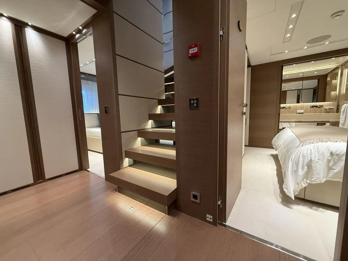 The image showcases a luxurious yacht interior with a modern staircase leading to a well-appointed stateroom. aboard PHOENICIAN Yacht for Sale