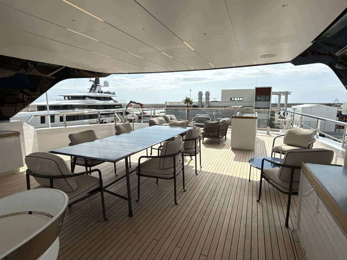 The aft deck features a spacious seating and dining area with a view of the marina. aboard PHOENICIAN Yacht for Sale