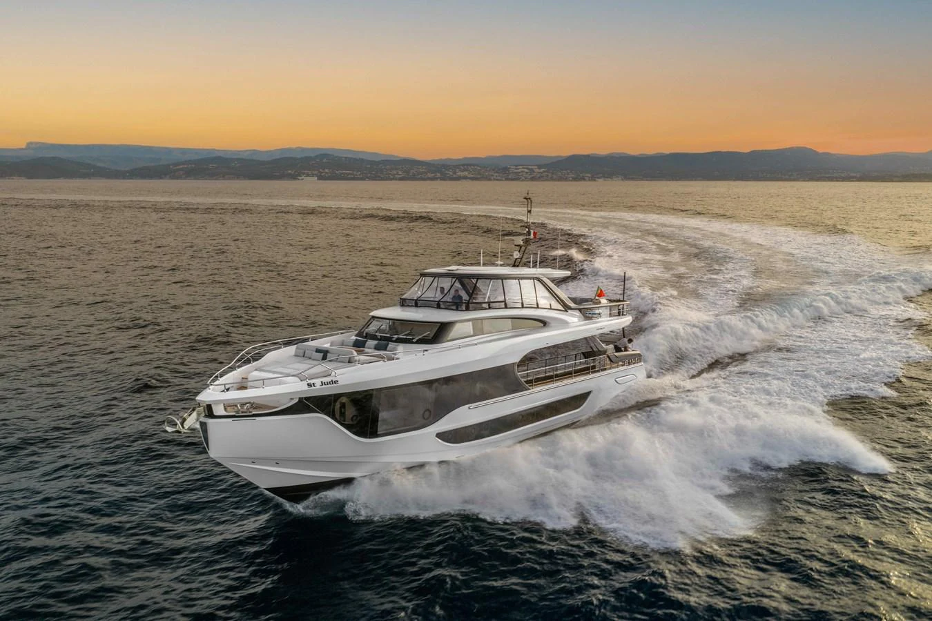 A sleek yacht cruises swiftly through the water at sunset. aboard ST JUDE Yacht for Sale