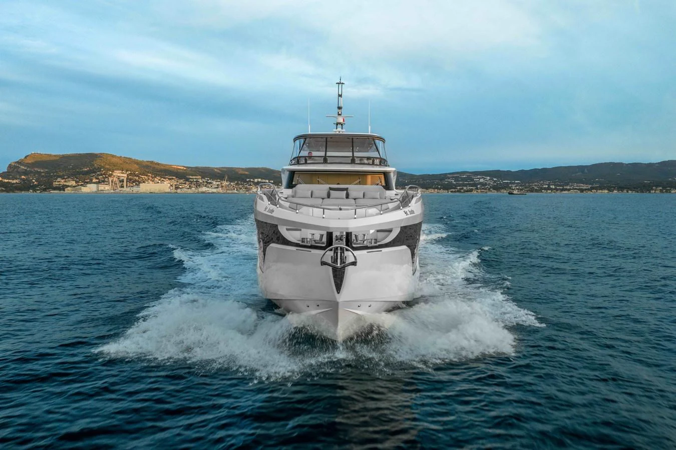 A luxurious yacht cruises forward on calm waters with a scenic coastline in the background. aboard ST JUDE Yacht for Sale