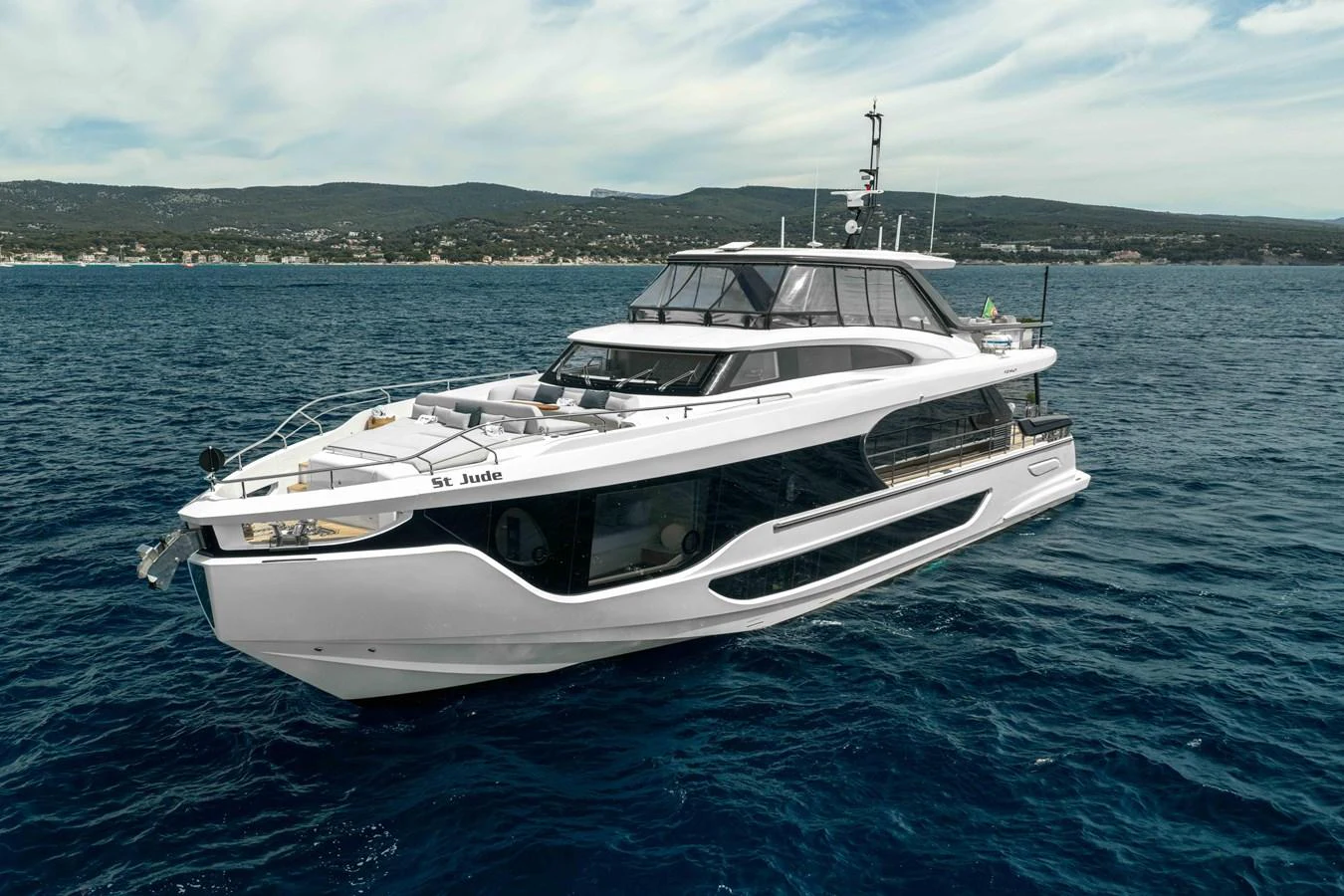 A sleek and modern yacht cruises on open waters with a scenic coastline in the background. aboard ST JUDE Yacht for Sale