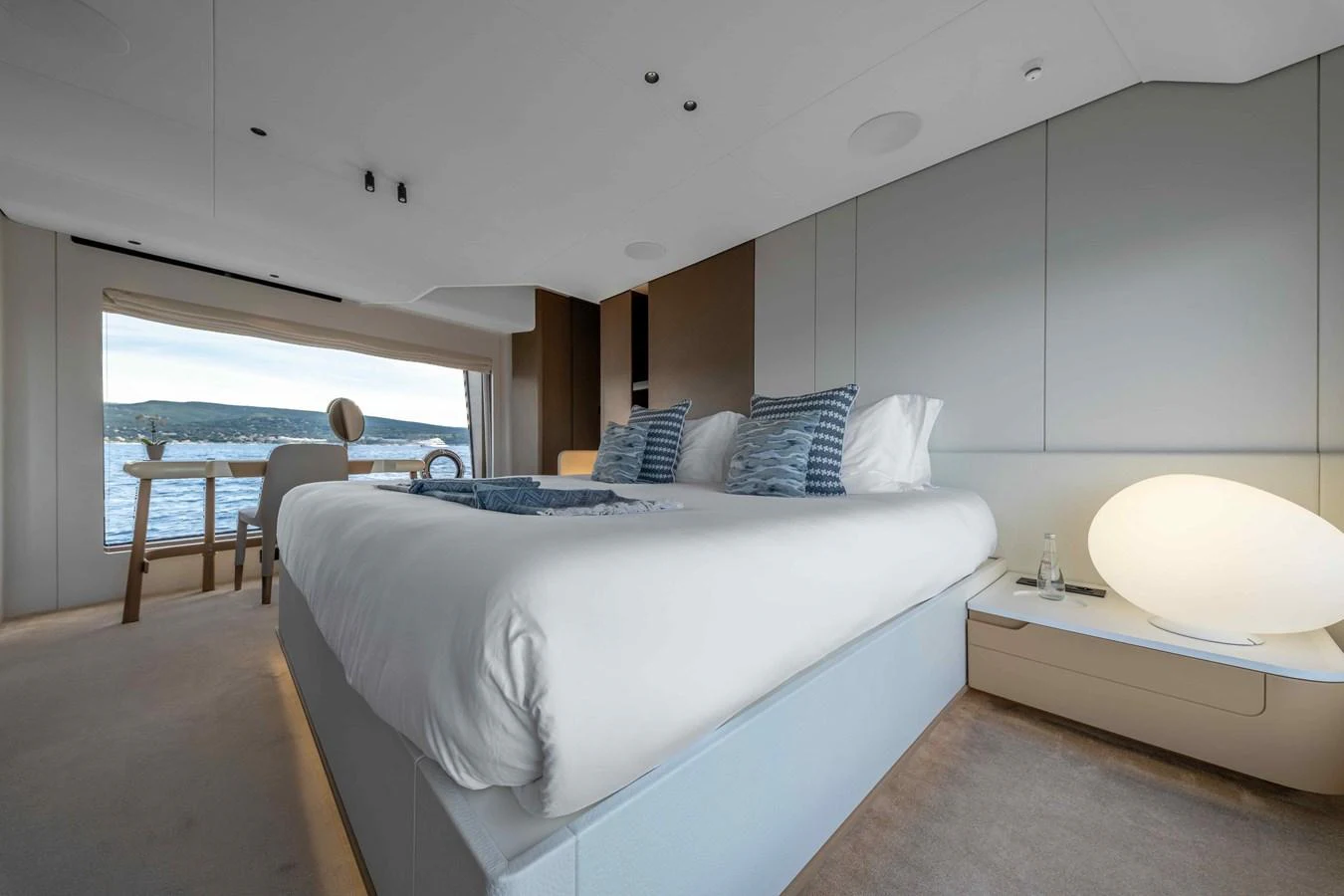 The master stateroom features a luxurious bed with a stunning view of the water through large windows. aboard ST JUDE Yacht for Sale