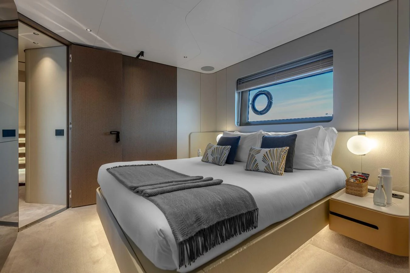 The stateroom features a plush bed with elegant decor and a view through a porthole window. aboard ST JUDE Yacht for Sale