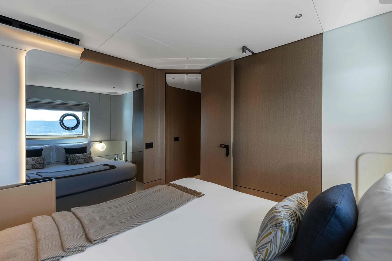 The stateroom features a comfortable bed with modern decor and a view of the sea through a porthole. aboard ST JUDE Yacht for Sale