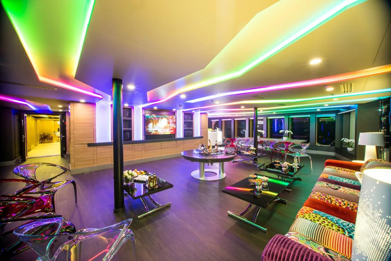 A vibrant and modern yacht interior with colorful LED lighting and stylish furnishings. aboard SALUZI Yacht for Sale