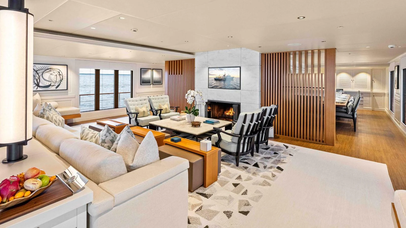 The spacious salon features elegant seating, a fireplace, and large windows offering stunning ocean views. aboard JUST B Yacht for Sale