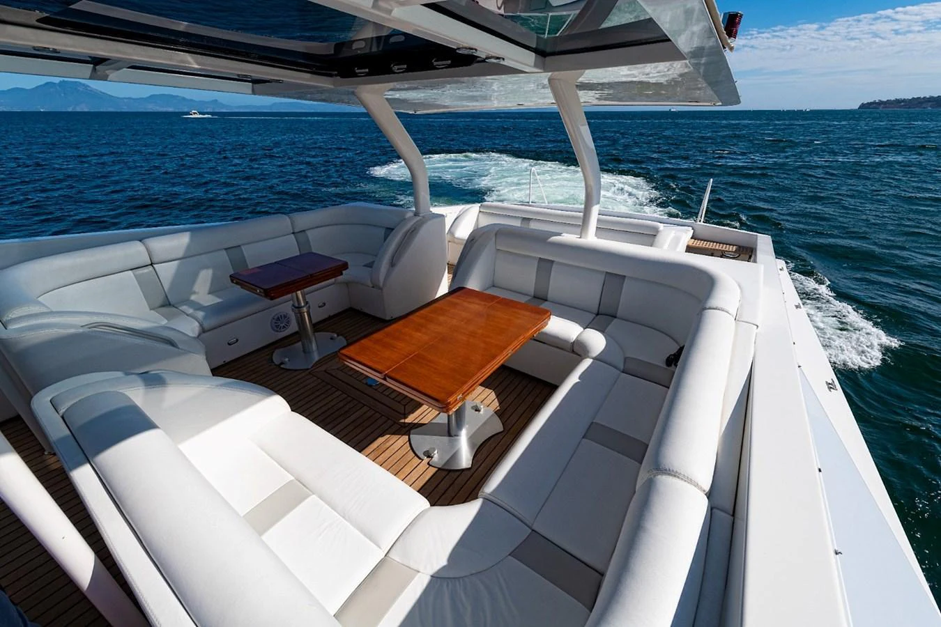 The aft deck features a spacious seating area with elegant wooden tables, perfect for enjoying the ocean views. aboard WHITE & SILVER Yacht for Sale