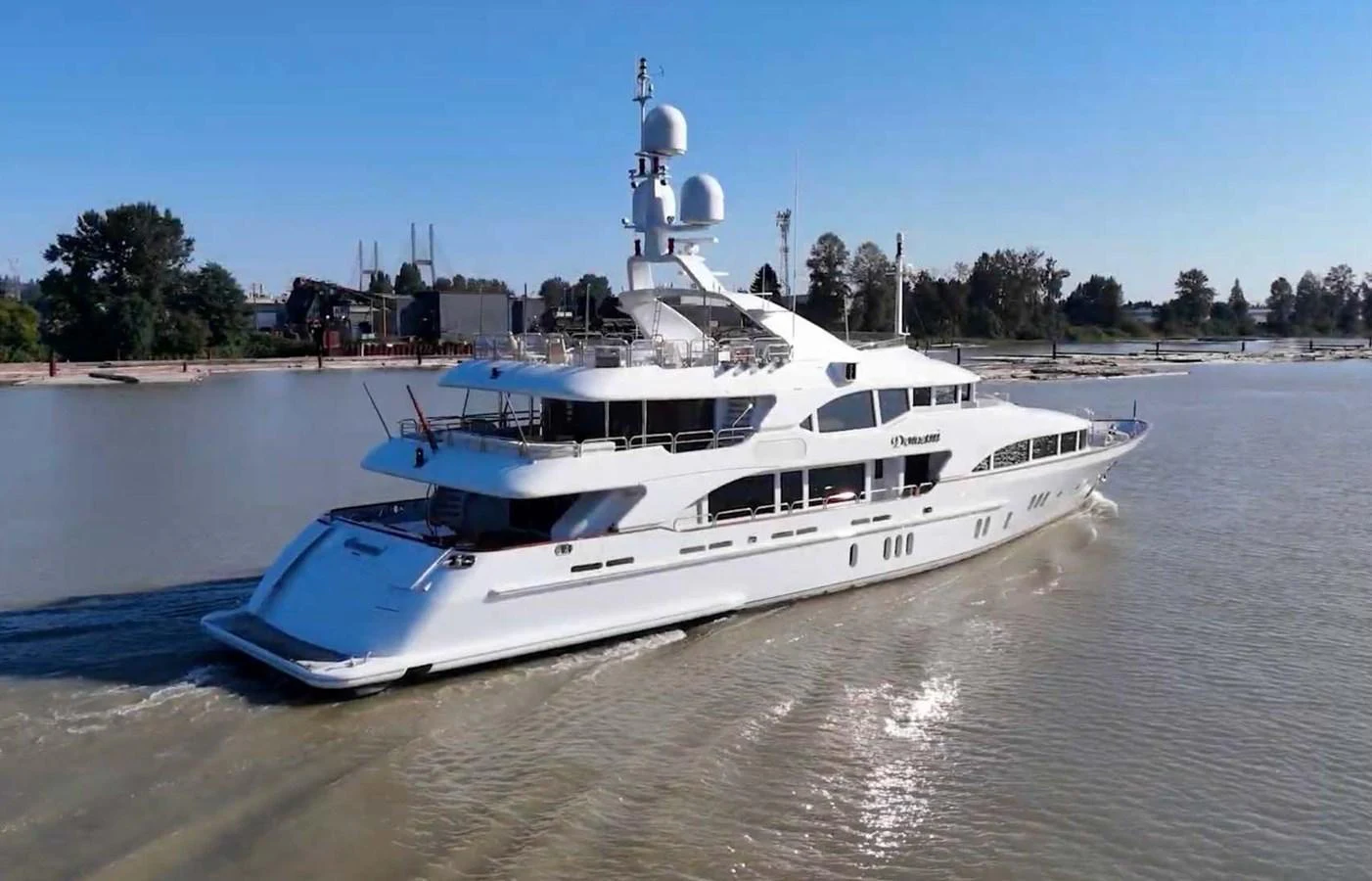 A sleek, modern yacht cruising through calm waters on a sunny day. aboard DOMANI Yacht for Sale
