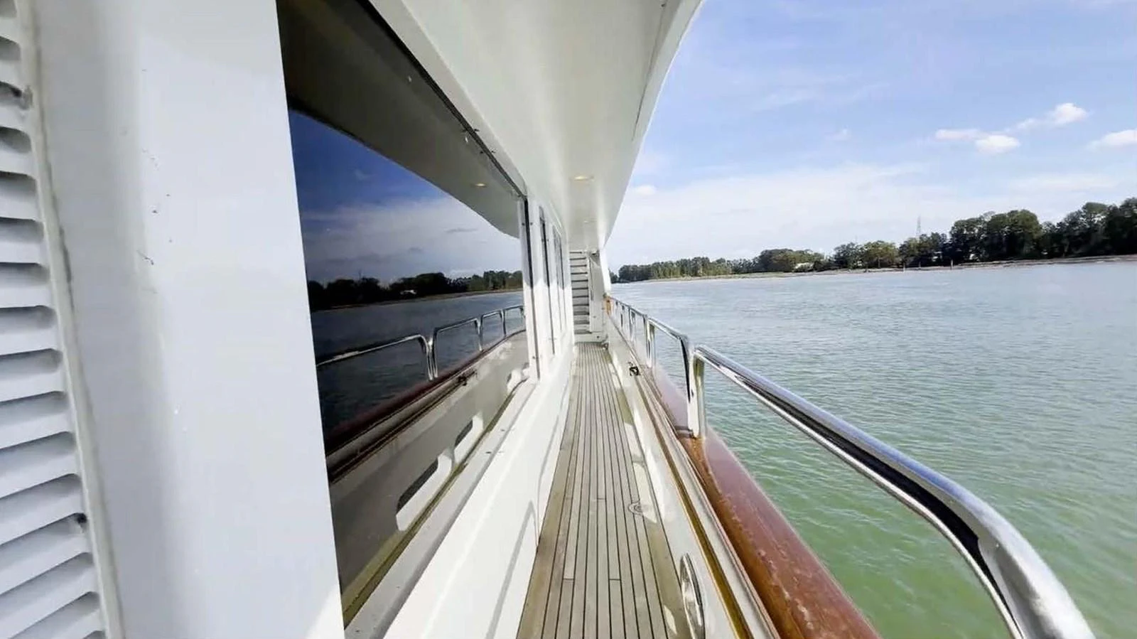 The side deck offers a serene view of the water and surrounding landscape. aboard DOMANI Yacht for Sale