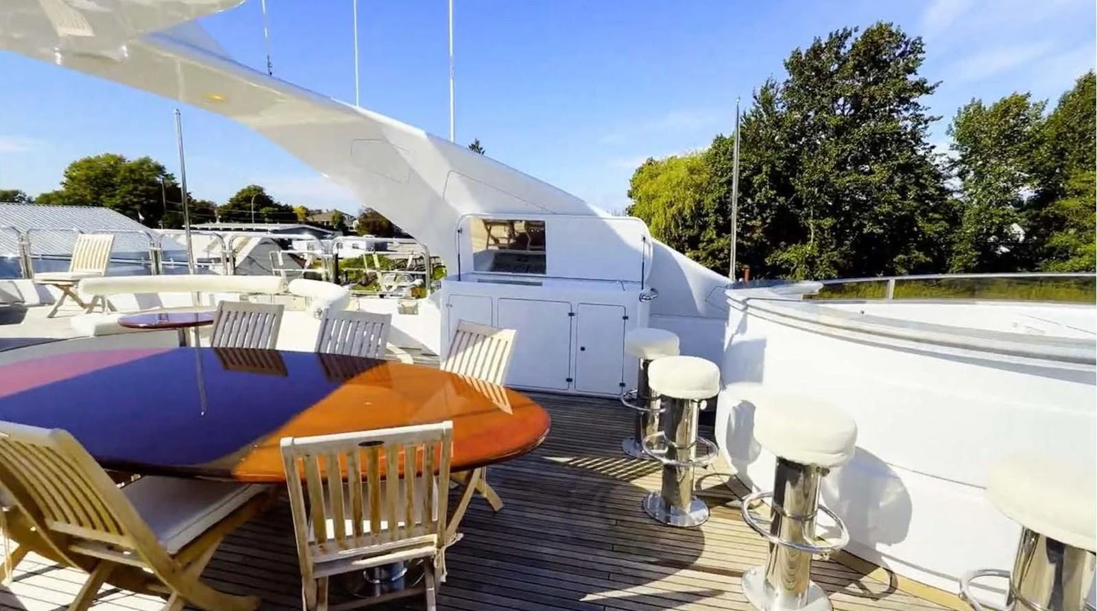 The sundeck features a spacious dining area with a polished wooden table and comfortable seating, perfect for outdoor meals and relaxation. aboard DOMANI Yacht for Sale