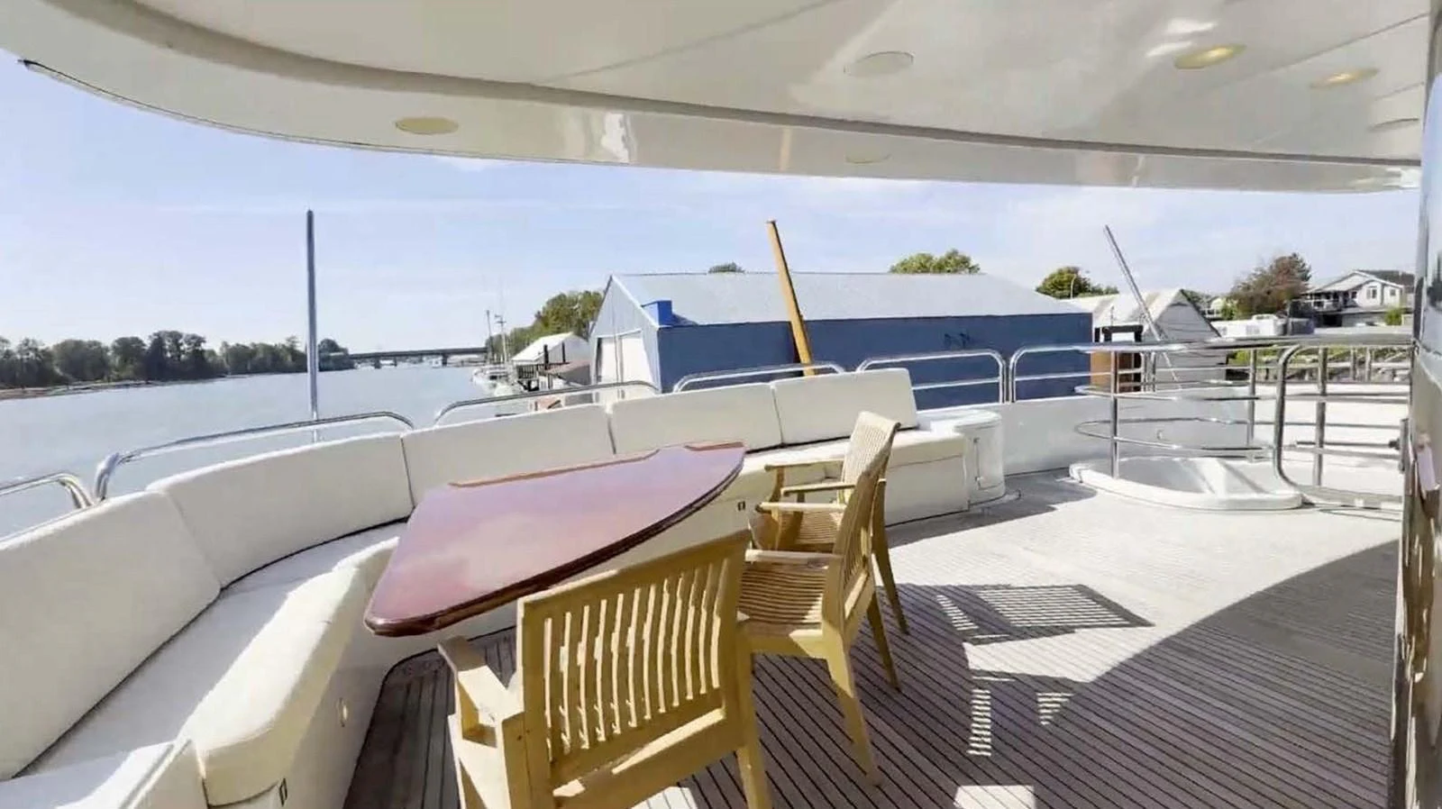 The aft deck features a spacious seating area with a wooden table and chairs, perfect for outdoor relaxation and dining. aboard DOMANI Yacht for Sale